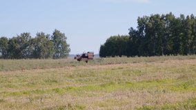 Blue wheeled combine harvester plowing a green field