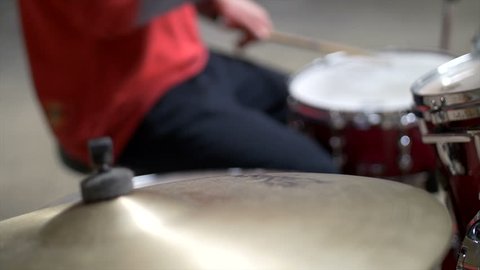 Blurred Close up of man playing drums in red outfit. Professional 4K UHD Shot