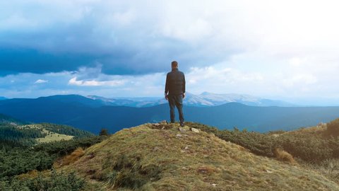 The male standing on the top of the mountain with a picturesque landscape
