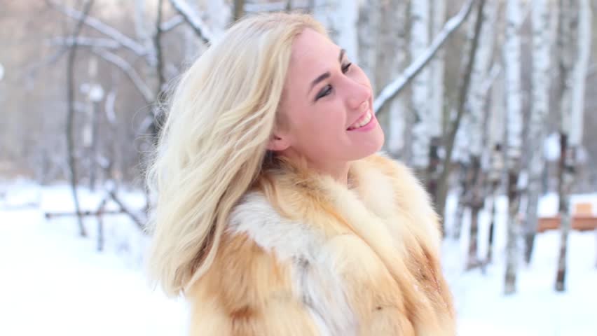 Pretty young blonde in fur coat smiles outdoor at winter day

