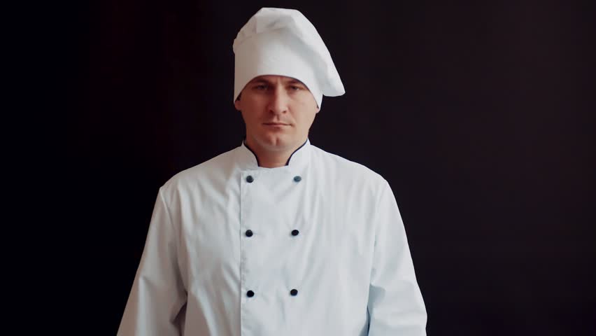 disgruntled angry chef with rolling pin in white kitchen suit on black wall background. concept idea of cooking Royalty-Free Stock Footage #1017123331