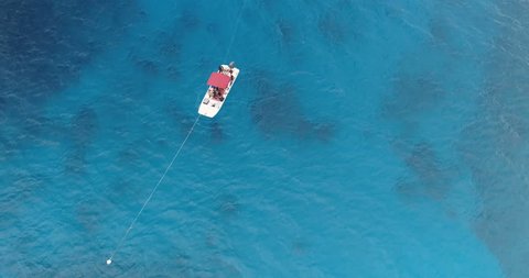 Aerial orbital view of boat full of divers on open ocean, clear blue water