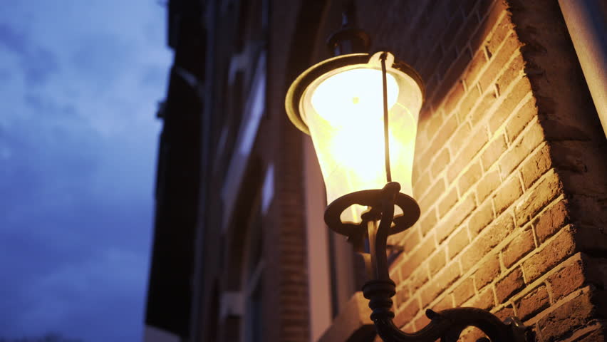 Twilight in Amsterdam illuminated street. Close up of a street wall with lighted lantern in vintage style