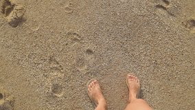 Top view shot of woman standing on sandy beach in Egypt. View from above tanned female feet wearing flip flops shoes. Real time full hd video footage.