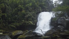 Whitewater roars over the brink of a natural waterfall in this tropical rainforest wilderness near Chiang Mai. Thailand. with sound.