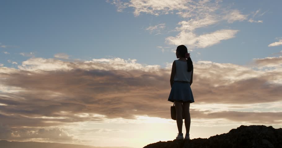 Silhouette of woman standing up to the mountain