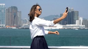 Happy businesswoman taking selfie photo with cellphone near river in city
