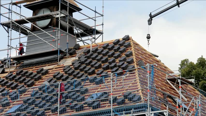 Truck Crane working on lifting tiles on the roof of the restored house