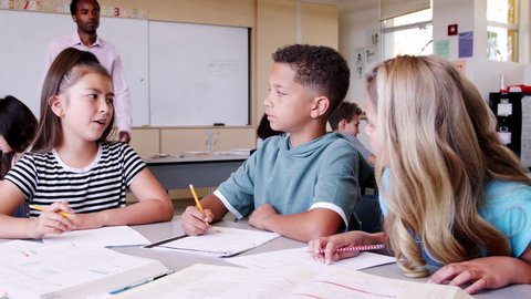 Male elementary school teacher comes to kids\xEA desk to help