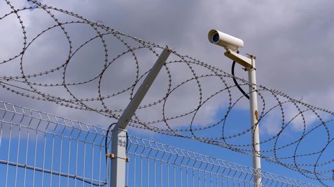 Concrete fence, barbed wire and surveillance camera