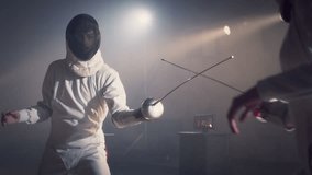 Footage video slow motion of two fencing athletes duel . Two Professional Fencers Show Masterful Swordsmanship in their Foil Fight. They Dodge, Leap and Thrust and Lunge . Shot on ARRI ALEXA in slow .