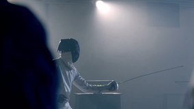 Footage video slow motion of two fencing athletes duel . Two Professional Fencers Show Masterful Swordsmanship in their Foil Fight. They Dodge, Leap and Thrust and Lunge . Shot on ARRI ALEXA in slow .
