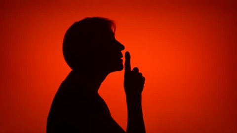 Silhouette of senior woman on red background. Female's face in profile put finger to lips making silence gesture. Black contur shadow of grandmother's half-face shush. Concept of mystery and secrecy