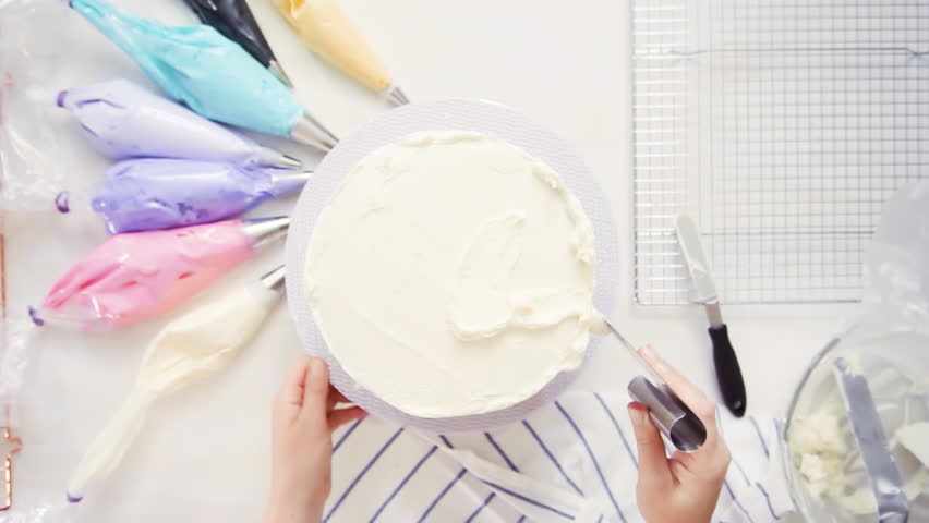 Step by step. Top view. Pastry chef stacking cake layers with buttercream frosting between to create unicorn cake. | Shutterstock HD Video #1017193294