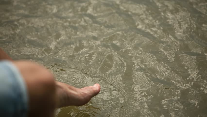 Beautiful youn couple sit on the pier near the lake. make splash by feet. slow motion