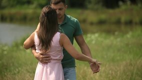Beautiful couple dance in the field. the enjoy each other and smile. Summer weather. Romantic atmophere. slow motion