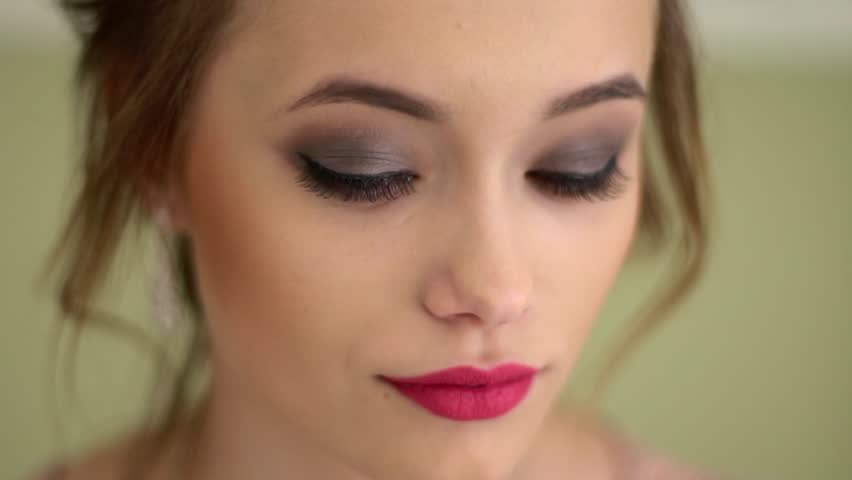A beautiful, modest Russian girl looks up and looks into the camera. Brightly colored scarlet lips, beautiful makeup. Big close up. Royalty-Free Stock Footage #1017194524