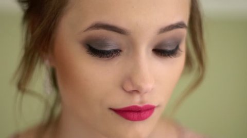 A beautiful, modest Russian girl looks up and looks into the camera. Brightly colored scarlet lips, beautiful makeup. Big close up.