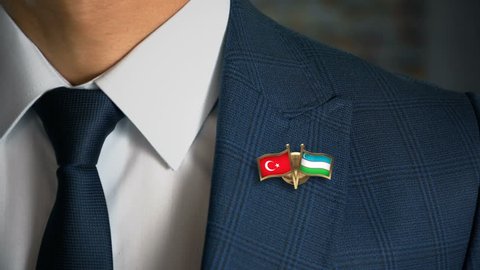 Businessman Walking Towards Camera With Friend Country Flags Pin Turkey - Uzbekistan