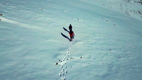 Aerial drone footage of two hikers climbing the summit of a snowy mountain