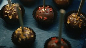 Delicious chocolate bonbon candies on sticks served on black slate chalkboard in cafe.Tasty sweet dessert food in bakery.Enjoy rich cocoa candy taste in restaurant