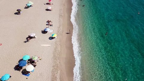 Aerial drone bird's eye view video of popular beach of Karavostasi with turquoise sandy beach full of sunbeds at summertime, Epirus, Ionian, Greece