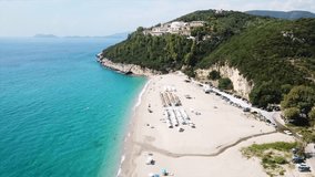 Aerial drone bird's eye view video of popular beach of Karavostasi with beautiful clouds and turquoise sandy beach full of sunbeds at summertime, Epirus, Ionian, Greece