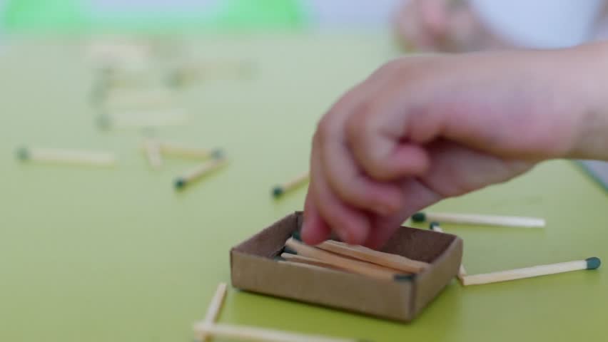 A small child plays with matches on the table, white background, caucasian, danger, hands of the child, close-up Royalty-Free Stock Footage #1017232174