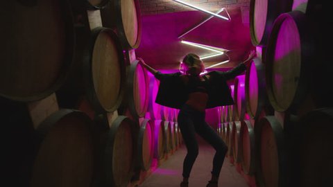 Hot girl dancing, walking . Dances with real strobe lights in colorful light winery with brandy , whiskey or wine barrels . Sexy body posing in wine house .  Clubbing scene in slow motion .