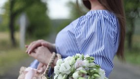 Close up view of beautiful pregnant woman in field holding bouquet and smile. Relax in nature