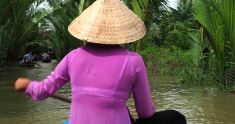 Mekong Delta, Vietnam - June 15, 2018: Vietnamese lady rowing sampan boat along the water coconut canals near My Tho in the Mekong Delta, a vast maze of rivers, swamps and islands in southern Vietnam.