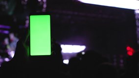 Chromakey greenscreen on smartphone, concert party rave background. Fans waving under the stage, scene highlights, technology innovations 4k