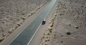SUV car is leaving on a highway on the background of the drought landscape of Death Valley in Nevada, USA. Aerial video recording.