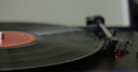 Womans hand places needle onto vinyl record carefully - close up