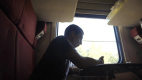 man silhouette travel is sitting on the train carriage holding sits by the window a smartphone Railway and drinking coffee and tea. slow motion video. man writes messages lifestyle in the smartphone