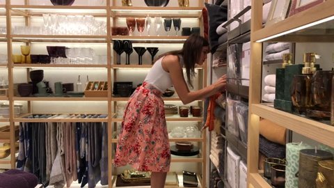 woman chooses accessories for a home in a store of goods, touching and examining
