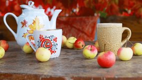Cup of tea with autumn leaves and apples on wooden table