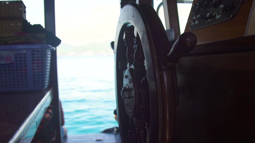 Close up steering wheel of sailing ship in captain bridge on blue sea landscape. Ship wheeel of sailing boat in sea