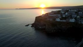Drone descends towards the harbor of Port Isaac in Cornwall during sunrise