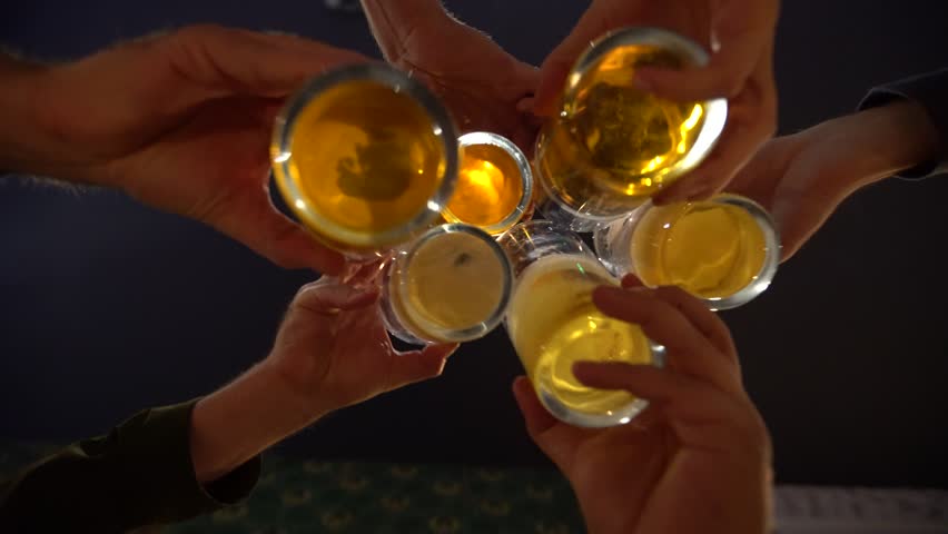 Men toast with the mugs of beer, bar at night. Alcohol and socializing. Pints of alcoholic lager drinks. Dark scene. | Shutterstock HD Video #1017296590