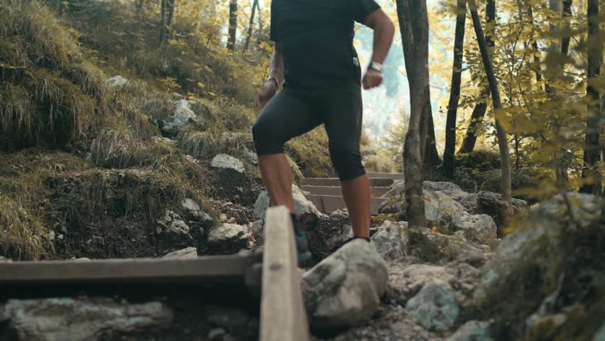 Older Man In Shape Jogging On The Steep Rocky Forest Slope In The Autumn, Running On The Wooden Stairs 