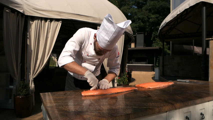 Chef is removing fish bone from salmon with tweezer