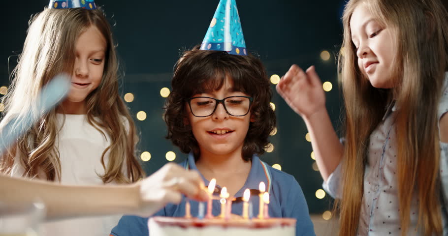 Kids at birthday party. Three little friends excited to blow out the candles on bithday cake, and cheering, having fun - happy childhood concept 4k