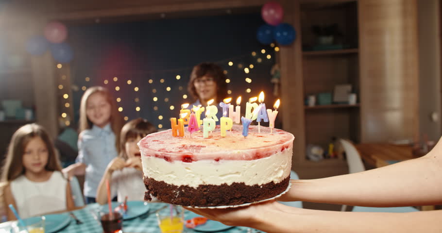 Children having birthday party, blowing out the candles on birthday cake. Group of kids celebraing birthday of their friend, cheering, having fun - happy childhood concept 4k