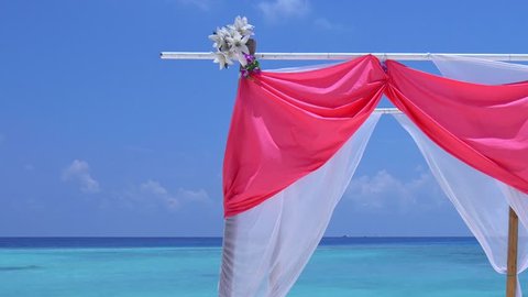 Wedding arch decorated with flowers and soft cloth. Marriage on tropical beach