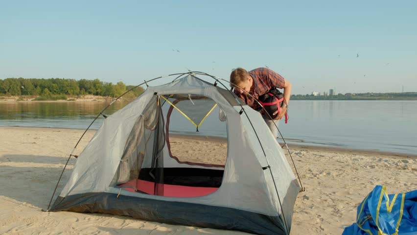 A mature man collects a tent on vacation outdoors near the sea 4k
