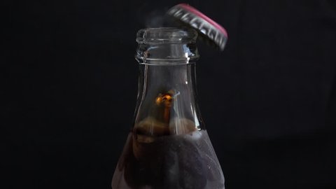 opens cola bottle with screw top. Slow motion shot against black background
