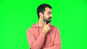 man with pink sweatshirt on green screen chroma key standing and looking down with the hand on the chin
