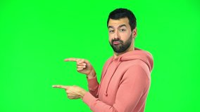 man with pink sweatshirt on green screen chroma key standing and looking to the side 