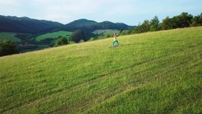 Aerial View Yoga woman is jogging in summer sunny day around trees and mountains background under sun light with blue sky, Drone 4K Video